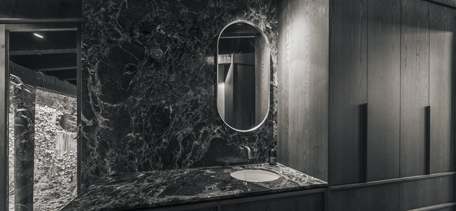 Dark marble bathroom with an oval mirror