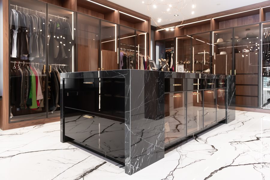 Walk-in closet with glass-front wardrobes and a black marble island