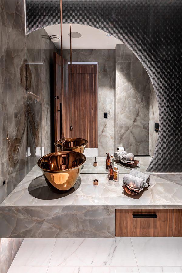 Powder room with a copper basin on a stone and walnut vanity