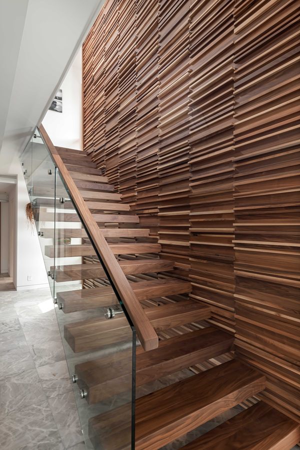 Sculptural walnut staircase wall with glass railing