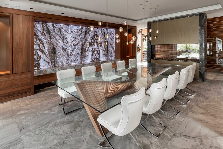 Dining room with a long walnut table and backlit stone feature wall