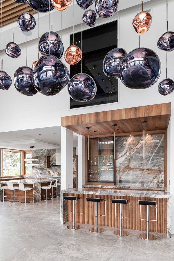 Walnut bar beneath a cluster of glass pendant lights