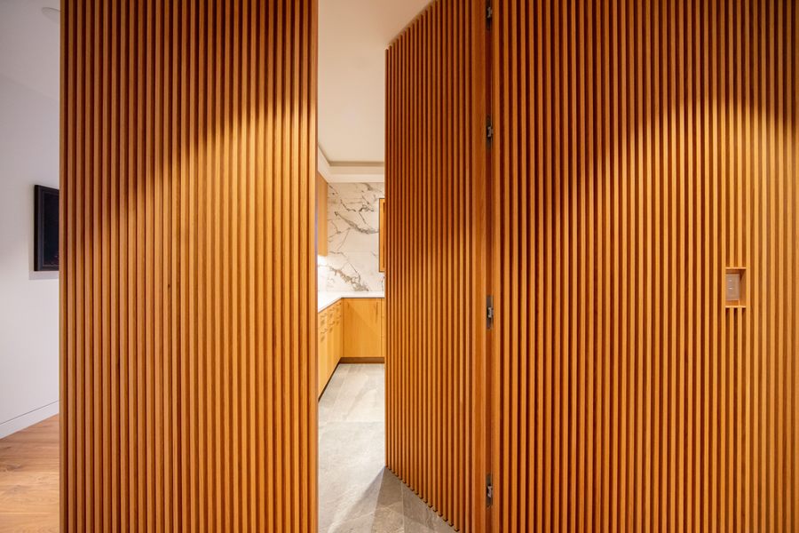 Full-height slatted walnut wall with a concealed door