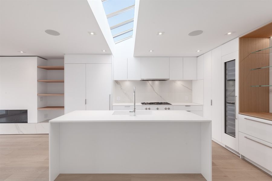 White kitchen with a large island under a skylight