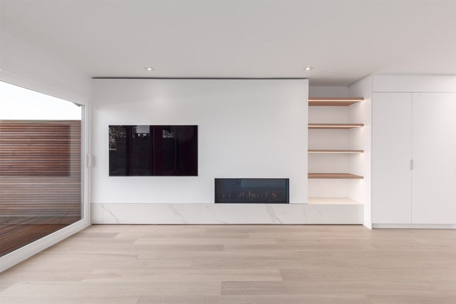 Living room media wall with fireplace and lit oak shelving