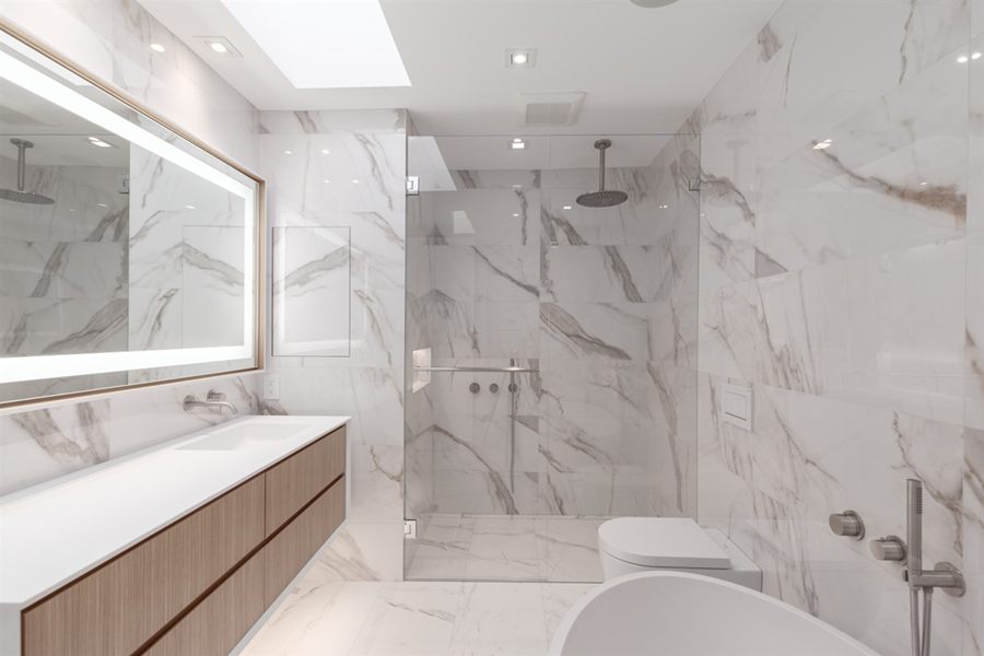 Marble ensuite with a floating oak vanity and lit mirror