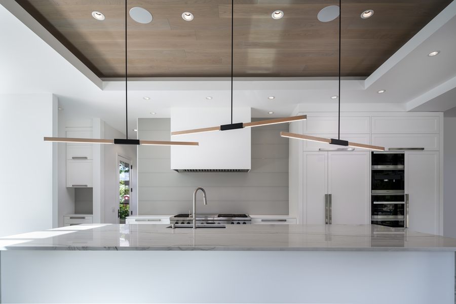 White kitchen with a waterfall island under a wood-slat ceiling