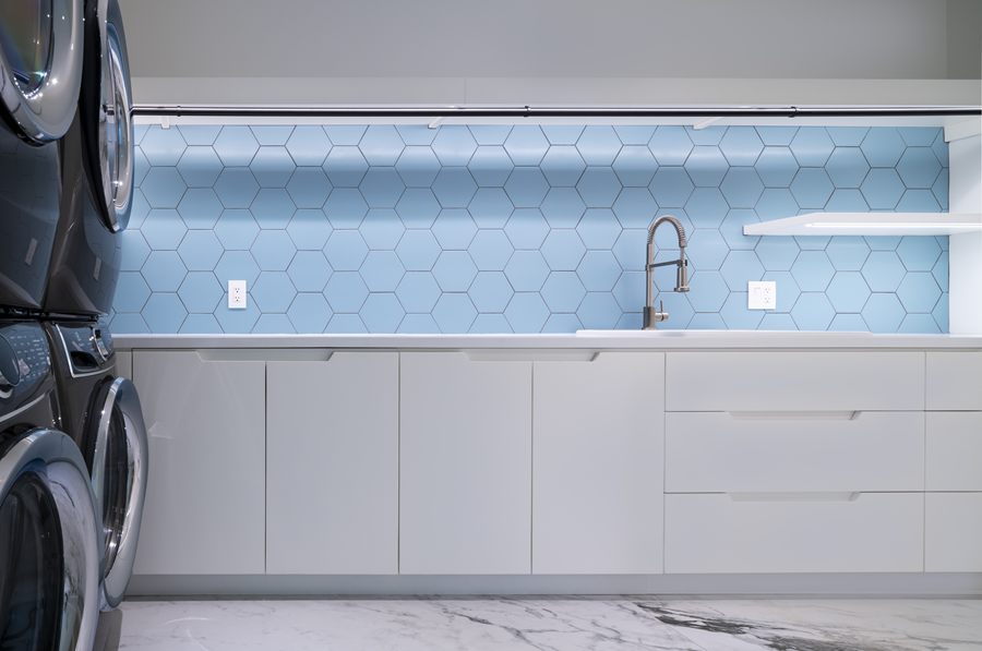 Laundry room with white cabinetry and blue hexagon tile
