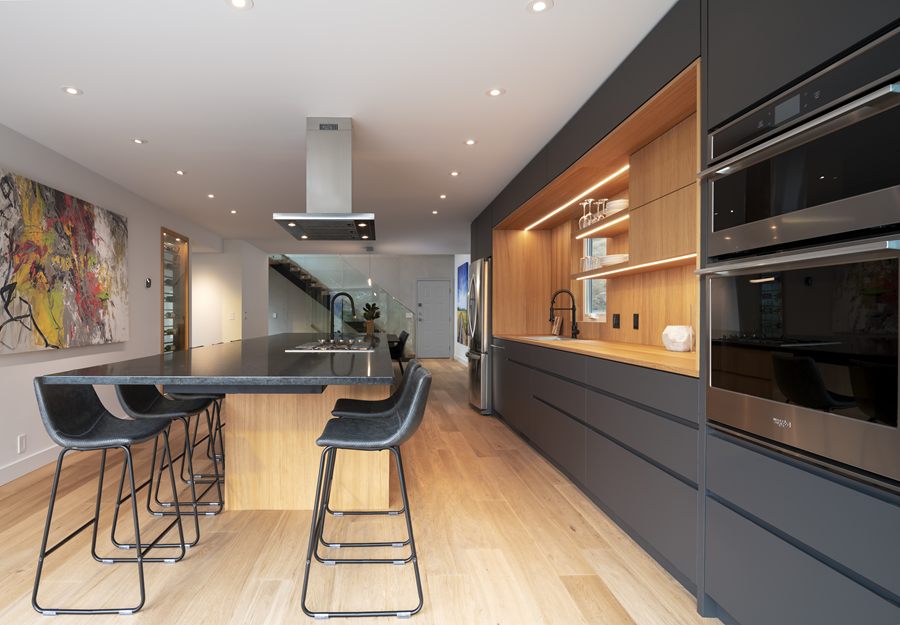 Charcoal kitchen with a lit wood shelving niche and bar seating
