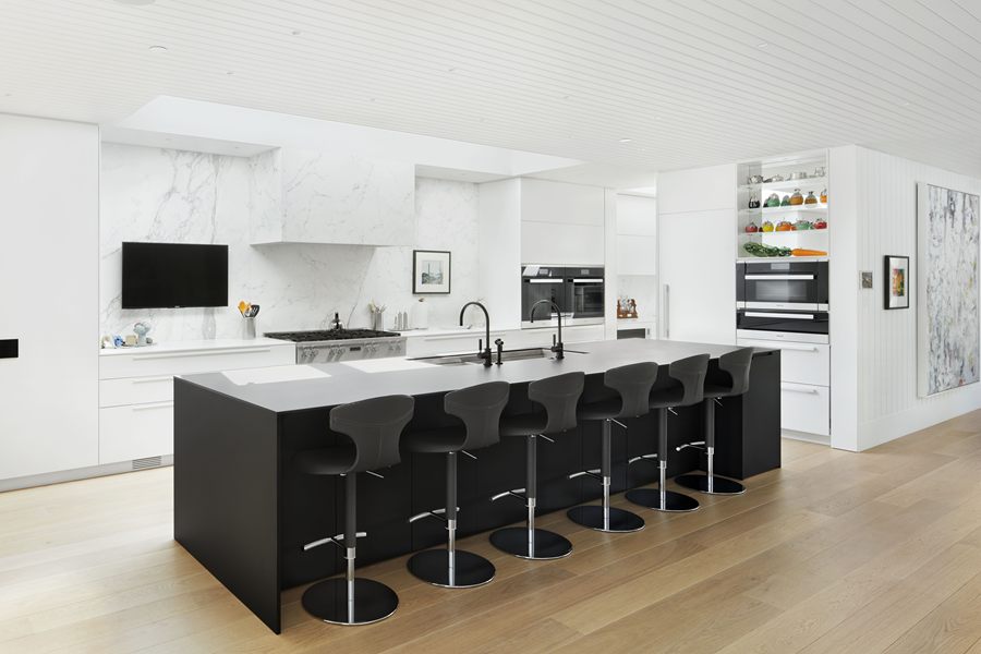 Skylight House kitchen with white cabinetry and a long black island with bar seating