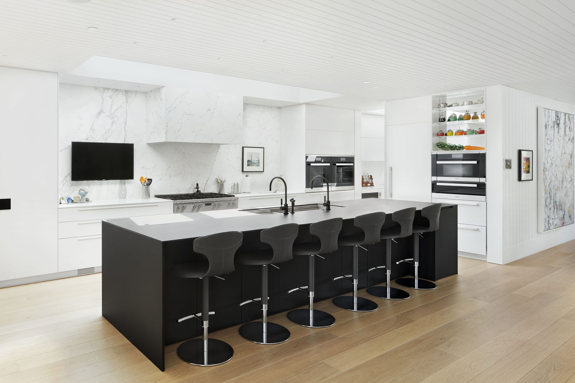 Kitchen with white cabinetry and a long black island with bar seating