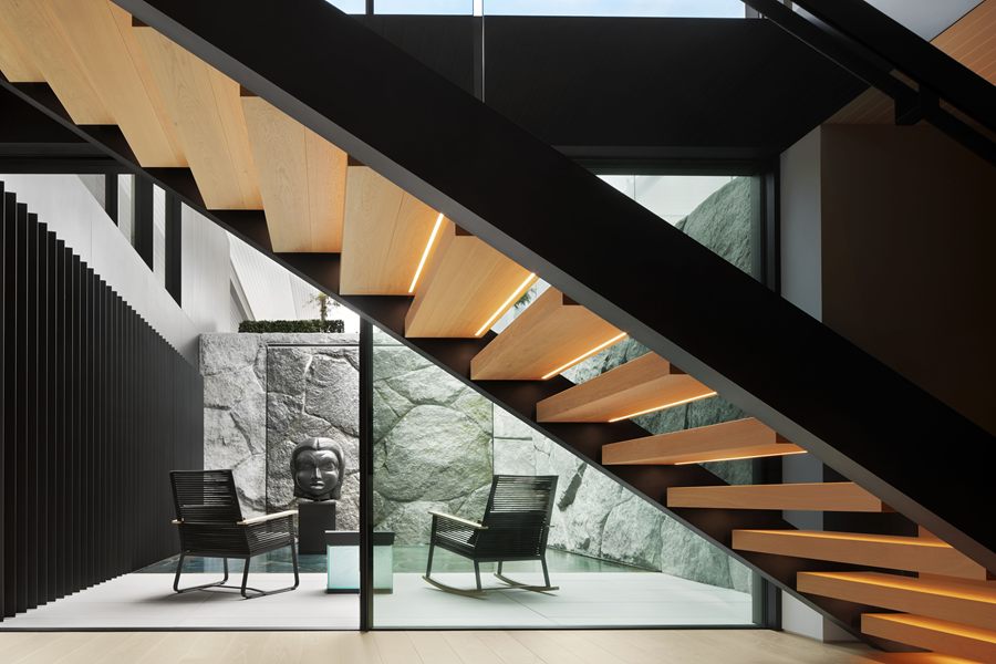 Open staircase with oak treads beside a glass wall