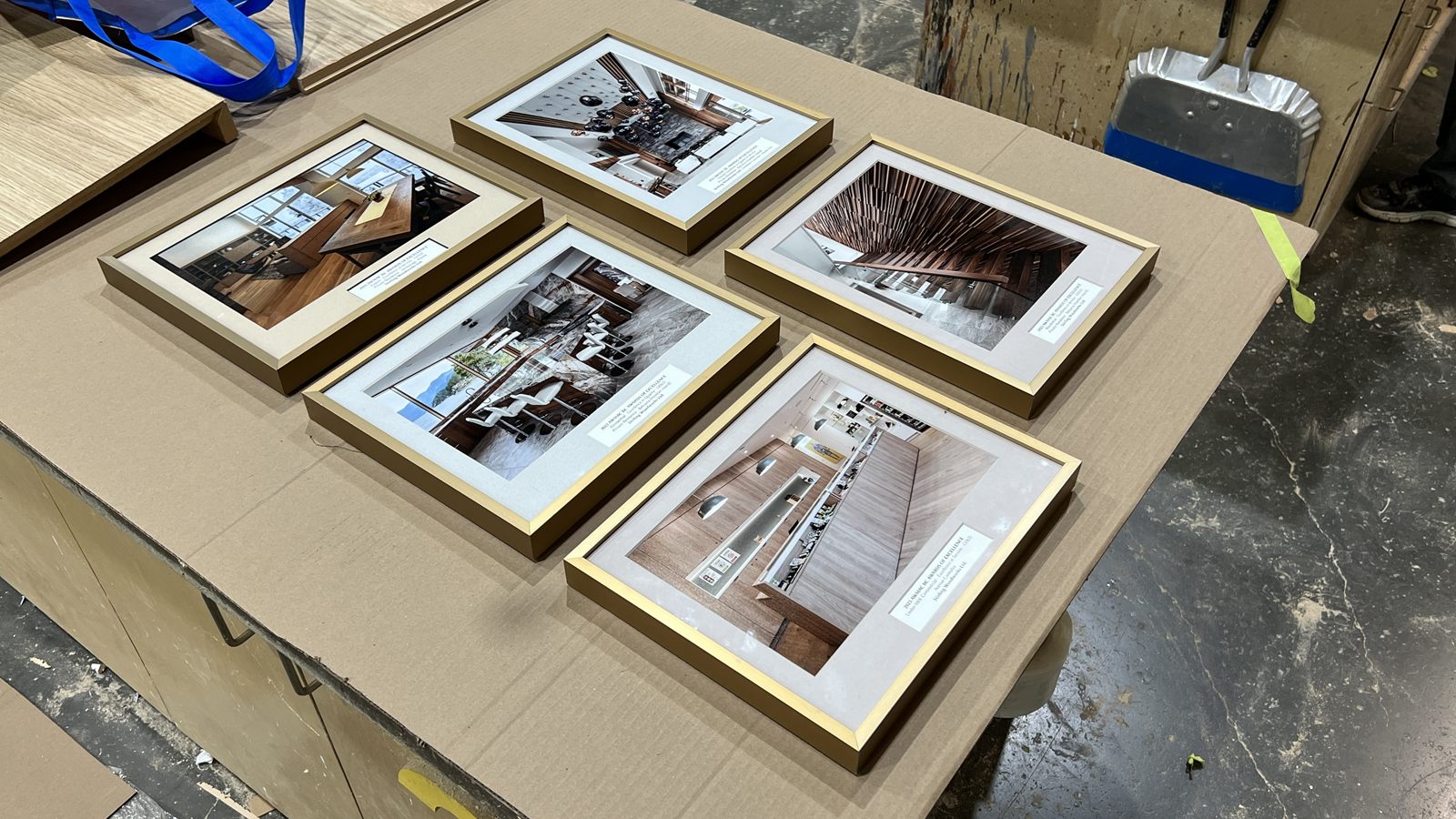 Framed AWMAC award photographs of Stirling Woodworks projects laid out on a table