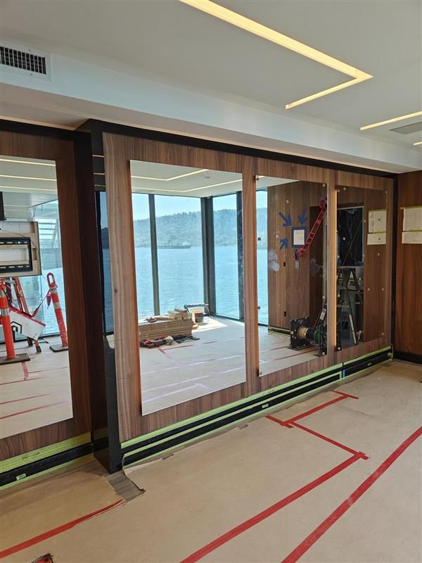 Walnut wall units being fitted in front of the lake-view windows